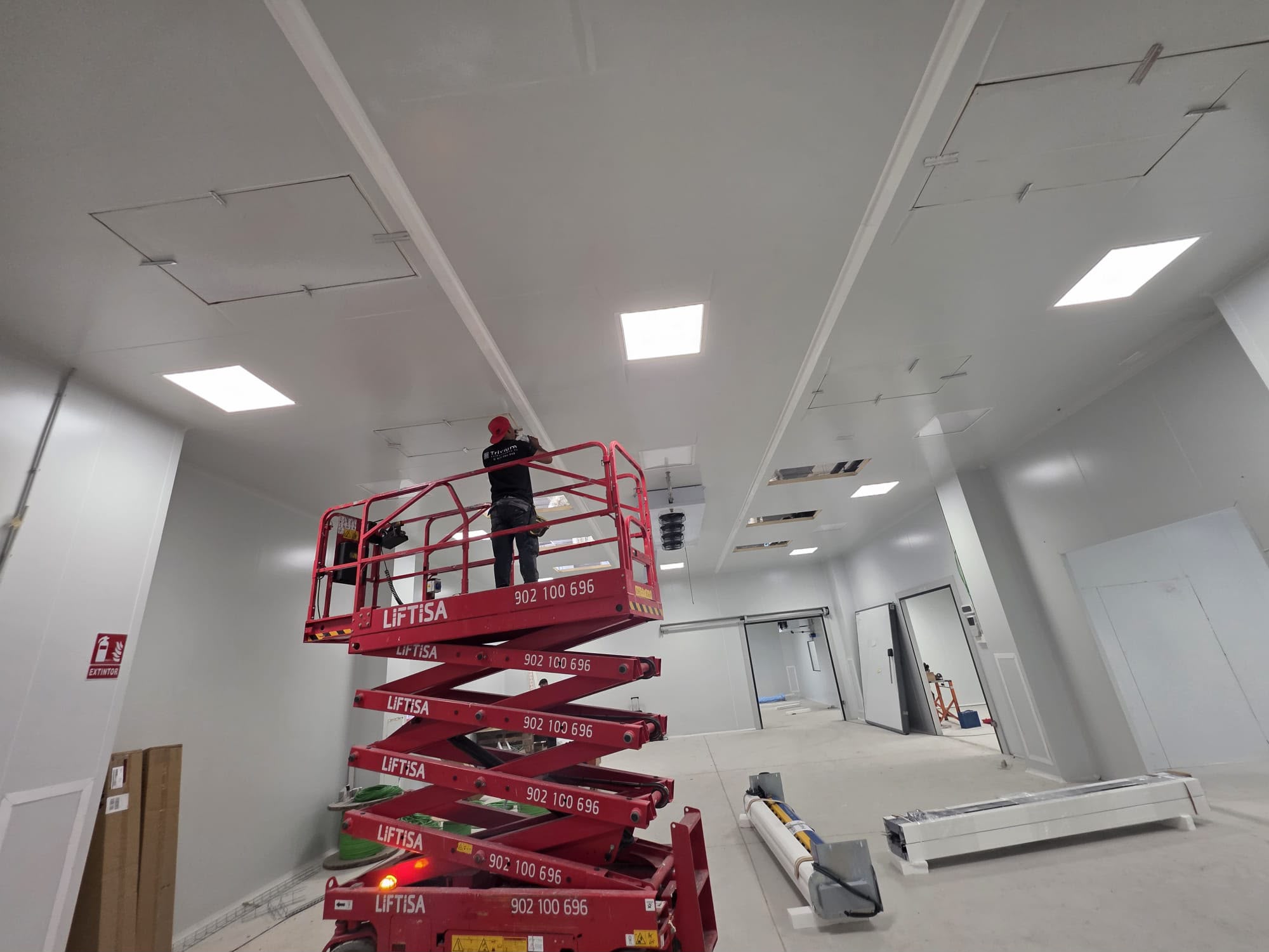 Operari muntant el sostre d'una sala blanca amb plataforma tisora